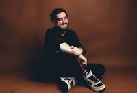 a man sitting on the floor with sneakers on his feet